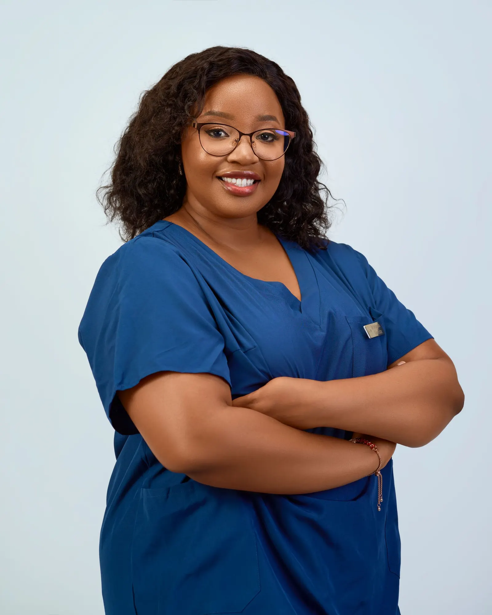 Smiling nurse in navy scrubs with arms folded