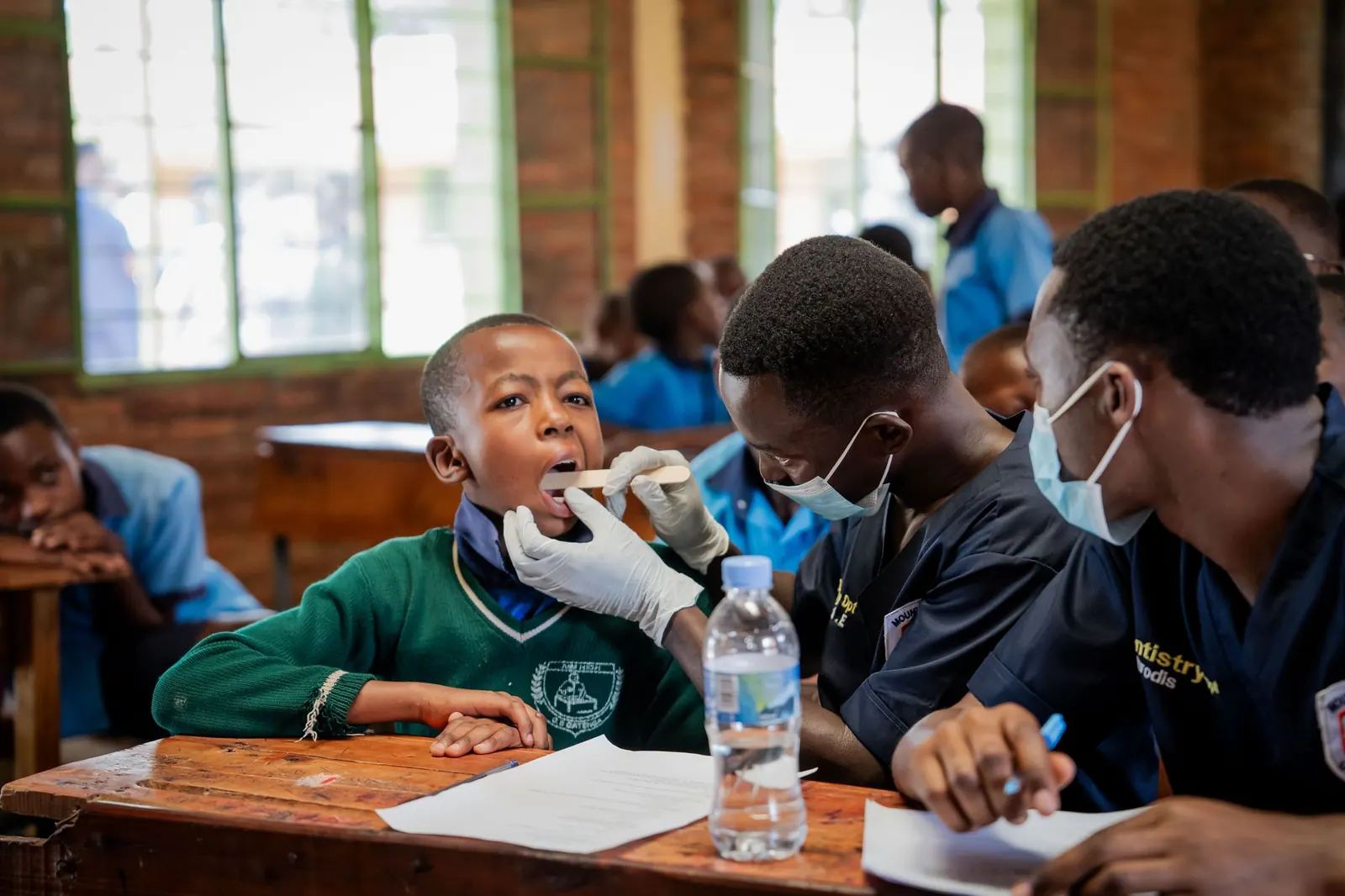 Young health volunteers checking a schoolboy's mouth during a school health check